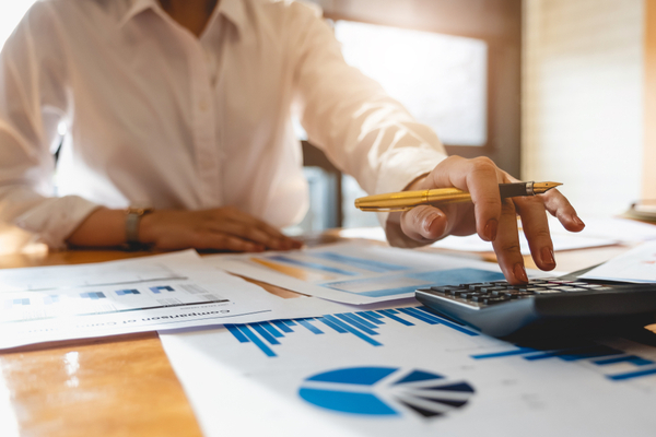 Woman using a calculator with graphs on the desk