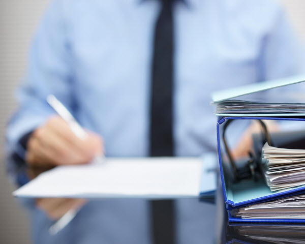 Binders placed on the table while a man in corporate attire checking a document